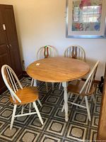 View of solid wood round drop leaf table with four matching chairs, natural wood tops and white painted legs.