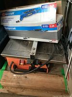 Boxed Mastercraft multi-crafter kit with tile cutter below it, both items with visible cords and working surfaces.