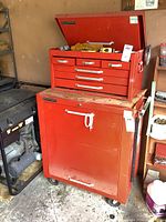 Red Mastercraft tool cabinet with drawer unit on top and items inside open drawer lid.
