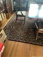Full view of floral pattern area rug under dining table and chairs, showing overall size and condition.