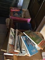 Three cardboard boxes filled with various worn books, predominantly focusing on birds, flowers, and nature subjects with visible illustration covers.