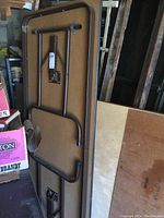 Photo of underside of catering table showing folding black metal legs and brown tabletop surface