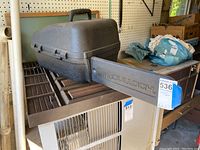 Closed black textured plastic hard case with top handle and side handle embossed with McCullough logo, sitting on a table with garage background.