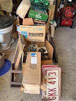 Empty cardboard boxes, wooden wall art shelves, and license plates in the lot.