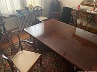 Photo showing the full dining table with six wooden dining chairs around it in a traditional style room.