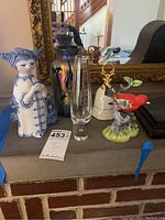 All five items displayed on mantel: ceramic lady figurine, iridescent vase, flute vase, porcelain bell, cardinal figurine
