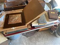 Multiple decorative storage cases stacked with the silver relief sculpture visible