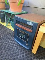 Photo of EdenPURE Elite heater positioned on carpet near potted plants and small table.