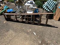 Complete wooden ladder laid on the ground outdoors showing full length and weathered surface.