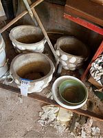 Full view of three concrete planters with white shell decorations and two ceramic bowls including green and white Haeger bowl.
