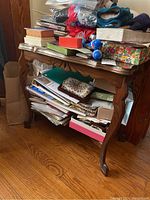 Front view of wooden side table filled with papers and other items (not included) showing overall surface and condition.