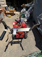 Front view of red Toro snowblower with black handle grips and metal frame, showing controls and ignition key switch.