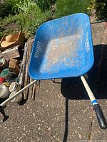 Blue metal Hechinger wheelbarrow showing inside basin with rust and wear, partial view