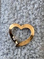 Close-up image of the 10K yellow gold heart-shaped pendant showing the polished gold surface and the small diamond accent.