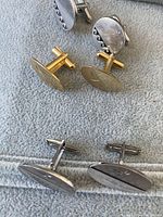 Photo showing all three pairs of cufflinks on a grey cloth background, highlighting shape and pattern details of each pair.