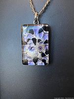 Front of classic rectangular Murano glass necklace pendant showing abstract purple, black, and silver patterns with a small floral millefiori detail.