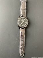 Front of Joan Rivers Classics watch with black face, silver numerals, and grey snake pattern leather strap.