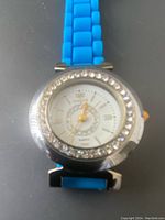 Front view of Joan Rivers Classics watch showing white dial with gold markers, crystal accents on bezel and blue silicone band.