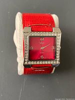 Front view of ladies quartz watch with red face and rhinestone bezel on red crocodile pattern wide leather-like bracelet