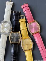 Front view of 4 ladies wristwatches with different colored leather straps and gold-tone cases, visible brand details unshown