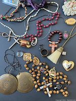 Full view of vintage jewelry lot showing assortment of necklaces, rings, pendants, medallions, and accessories spread on a dark surface.
