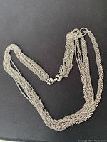 Image showing multi-layer silver tone necklace with multiple fine chains and central double ring clasp.