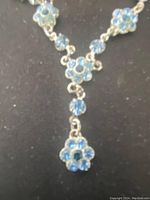 Close-up of blue rhinestone floral necklace segment showing detailed design and stone arrangement