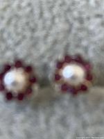 Close-up front view of garnet cluster sterling silver earrings with central silver bead on gray velvet background.