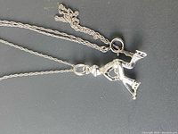 Clear photo showing the sterling silver necklace chain and pendant shaped like a human figure in motion