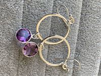 Close-up photo of sterling silver earrings with hammered hoops and two amethyst stones each, showing color and setting details.