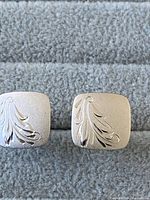 Front view of the pair of sterling silver square cufflinks with embossed leaf pattern on each.