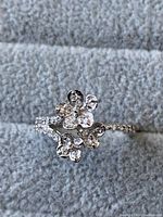 Close-up of the ring showing two flower designs with clear cubic zirconia stones on band and flowers.