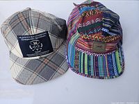 Two hats displayed together; one plaid with dark patch and one colorful patterned