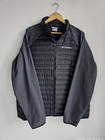 Front view of the men's XL black Columbia jacket showing quilted insulated front and smoother fabric sleeves, on a hanger.