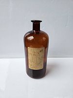 Full view of the amber brown glass bottle showing shape and size against a plain background.