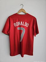 Back view of red Portugal jersey showing the name 'RONALDO' and number 7 in white on a red striped background.