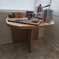 Full view of the wooden Danish table with various items placed on top, showing the rounded drop-leaf top and the base design.
