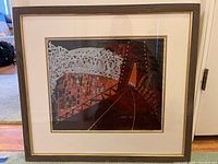 Framed print showing the entire artwork, depicting an abstract scene with geometric white shapes over a red and black background.