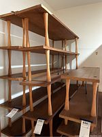 Front side view of mid-century modern style wooden bookshelf showing multiple rectangular shelves supported by round wooden tapered legs.