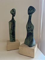 Front view of both sculptures against a white wall