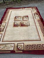 Full view of the large rectangular machine made rug showing floral and geometric borders and central design.