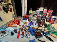 Lot showing various hand tools, spray cans and automotive fluids on a table