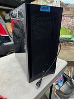 Front and right-side view of black Corsair case on table showing mesh front panel, power cable attached