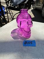 Amethyst skull-shaped bottle sitting on a surface in daylight, showing translucence and detail of the bottle.