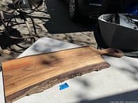 View of the cutting board laying flat to show full size, wood grain, live bark edge and handle.