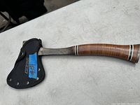 Eastwing axe showing the full axe with leather blade sheath on a white surface