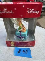 Front view of Hallmark Disney Tinker Bell Christmas decoration in original packaging showing figurine inside clear plastic display with red box.