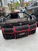 Front and side views of the Husky soft tool box bag showing exterior pockets, padded handle, and internal compartments.