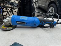 Side view of the blue Mastercraft angle grinder with grinding disc attached, showing body and power cord.
