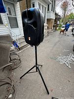 Rockville RPG122K speaker mounted on adjustable tripod stand outdoors near residential buildings.